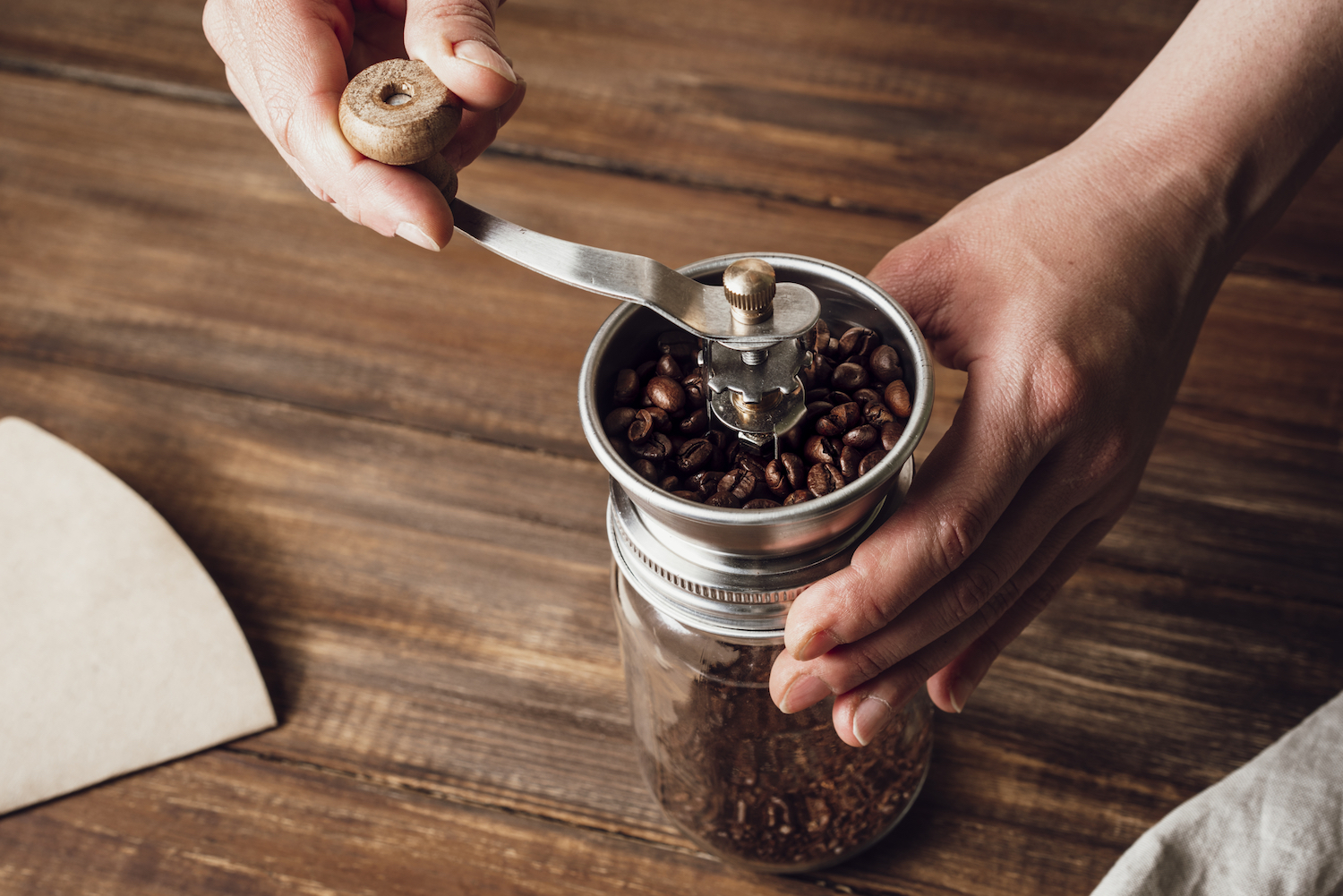 Manuelle Kaffeemühle mit Holzgriff und Metallmahlwerk auf einem Holztisch